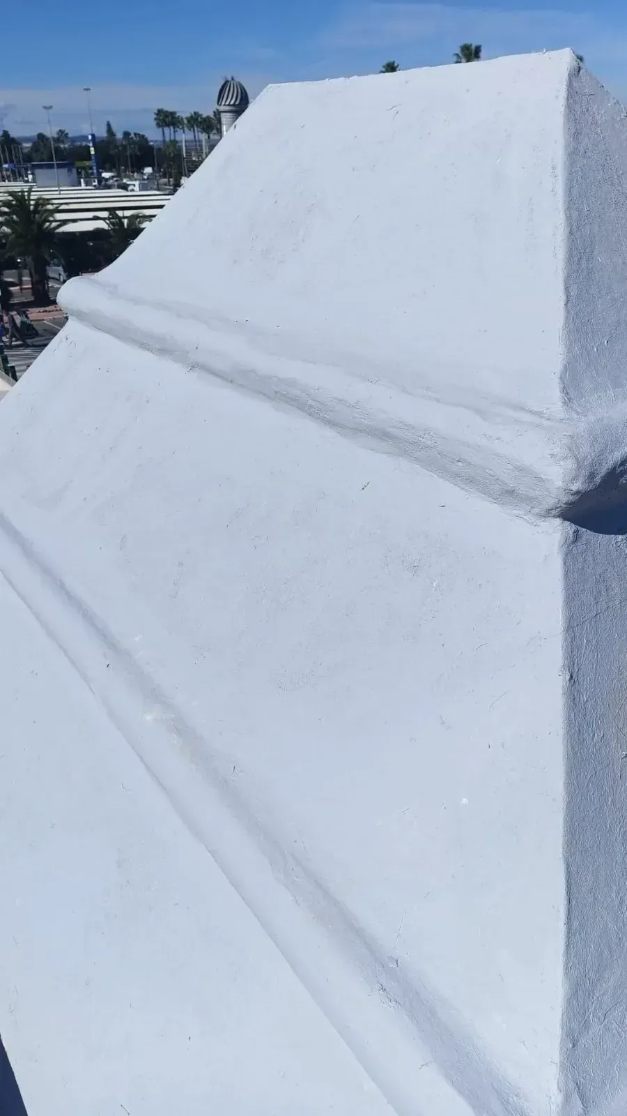 Un elemento arquitectónico de hormigón blanco, escalonado, posiblemente un remate de chimenea,.