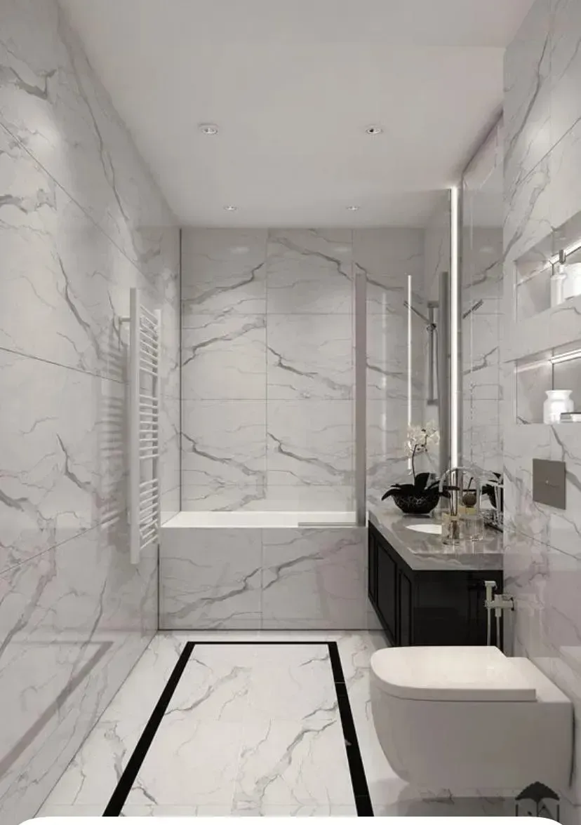 Un baño moderno y estrecho con paredes y suelo de mármol blanco con un borde rectangular incrustado de color negro.