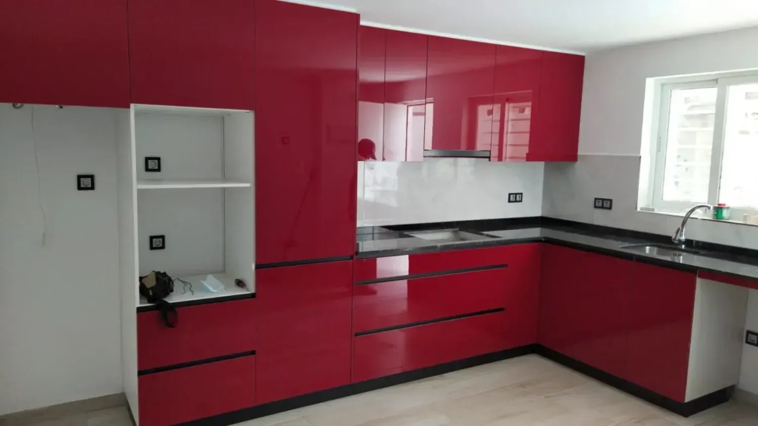 Cocina moderna con gabinetes rojos de alto brillo, un protector contra salpicaduras blanco, encimeras claras .