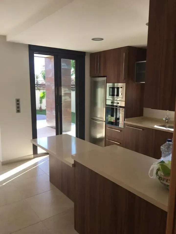 Una cocina moderna con armarios de madera oscura, encimeras de piedra clara, una barra de desayuno .