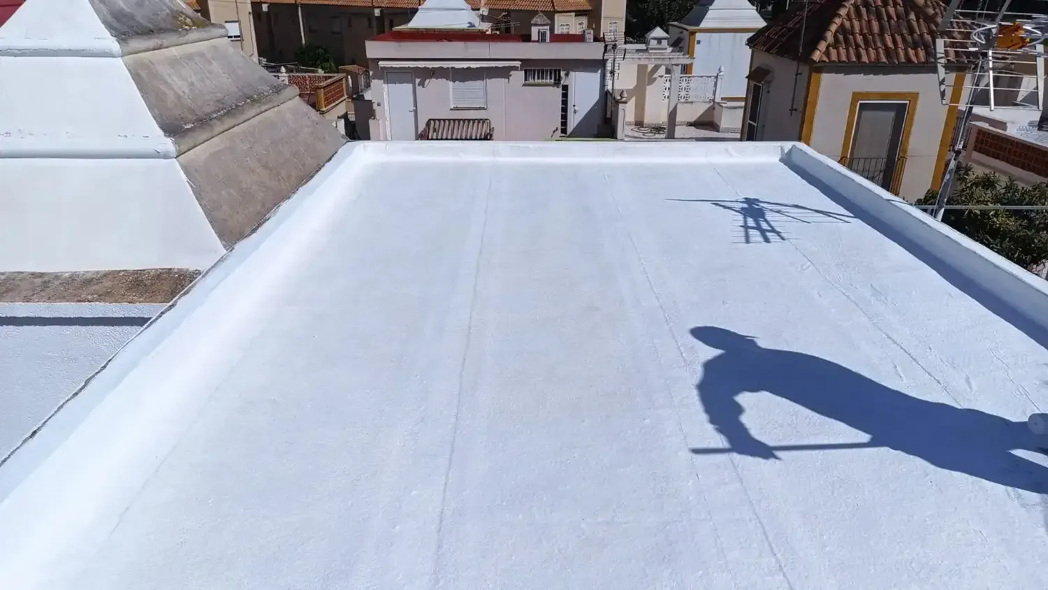 Una capa de revestimiento blanco liso e impermeable recién aplicada sobre una azotea plana, con la sombra.