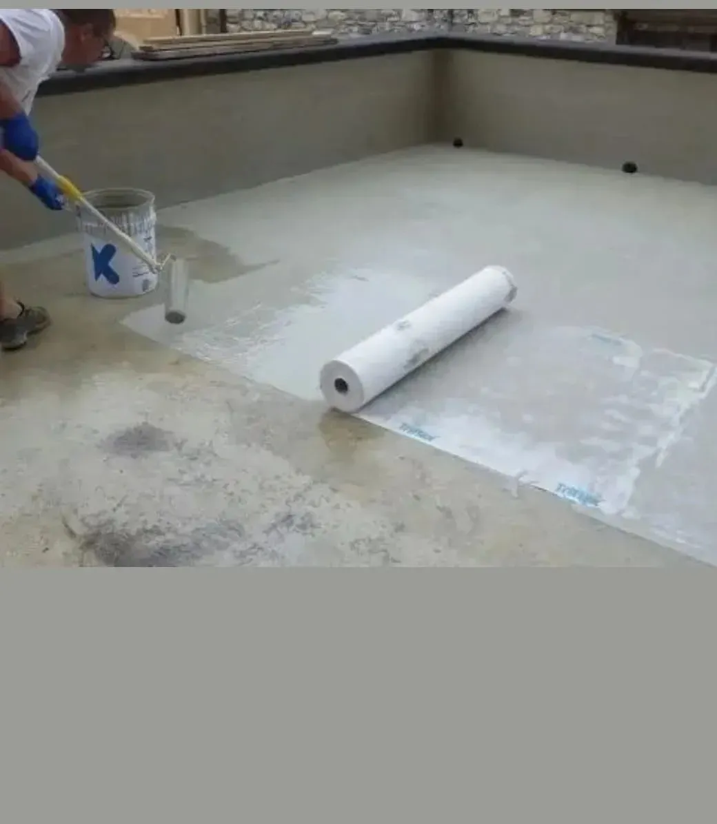 Un trabajador aplica un sellador líquido a una superficie plana y extiende una capa .