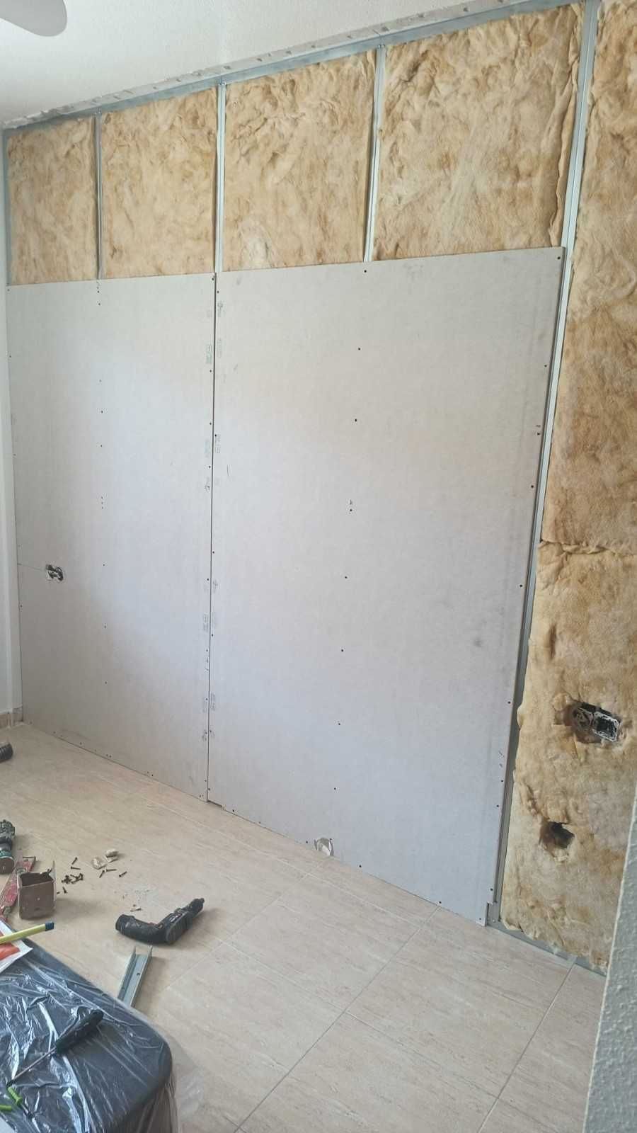 Una pared en construcción con montantes metálicos, aislamiento amarillo a la vista.