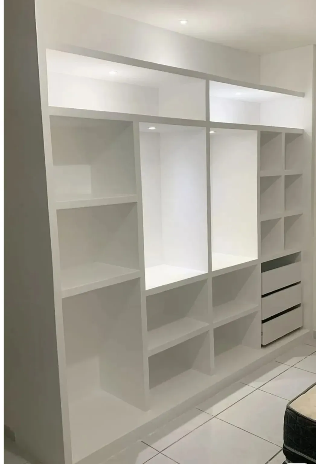 Una estantería empotrada grande y blanca con varios compartimentos de almacenamiento abiertos.