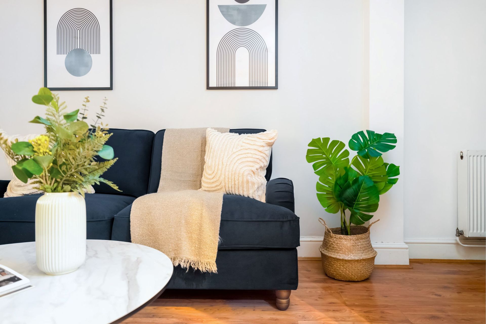 A living room with a couch , coffee table , and potted plants.