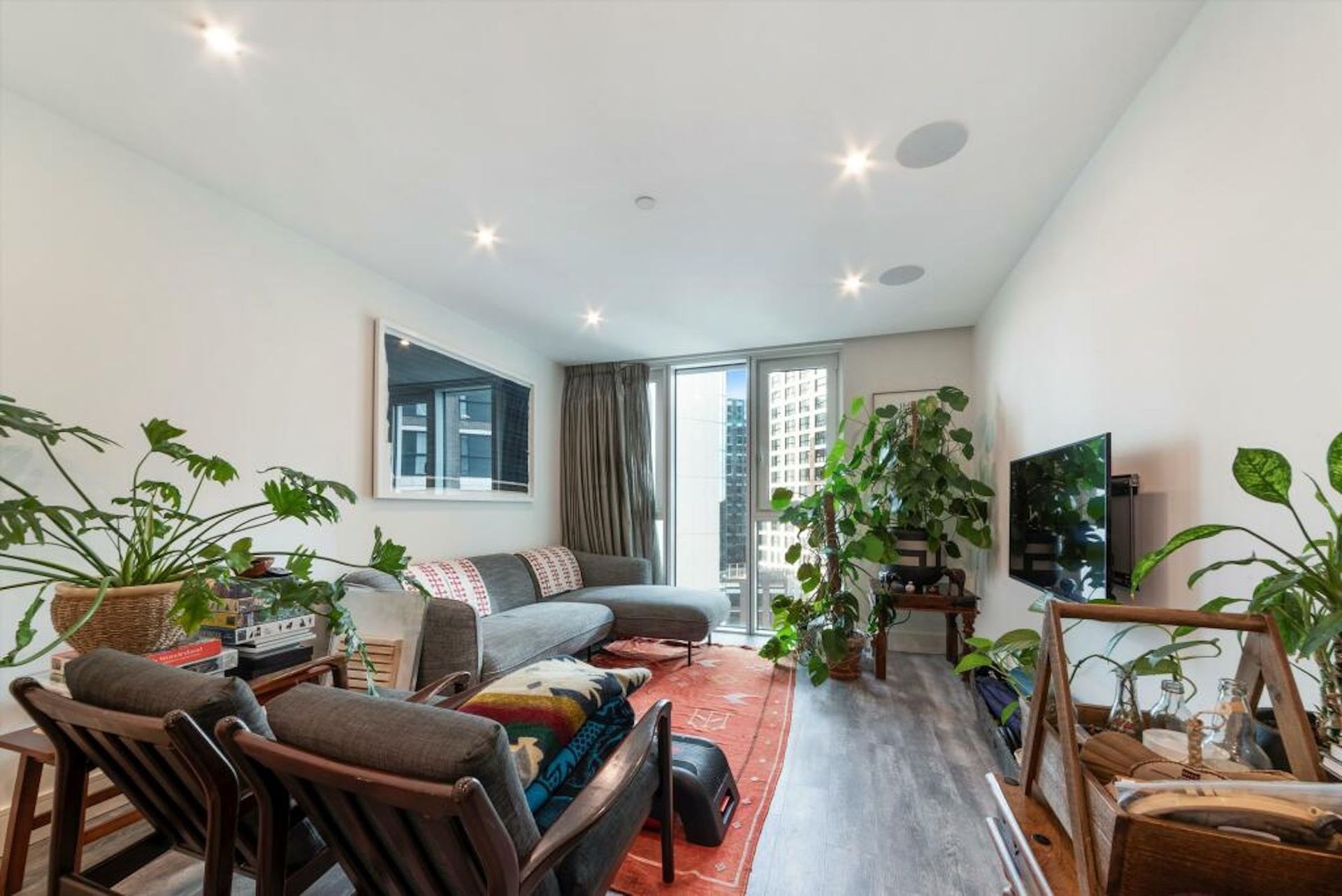 A living room with a couch and chairs and plants