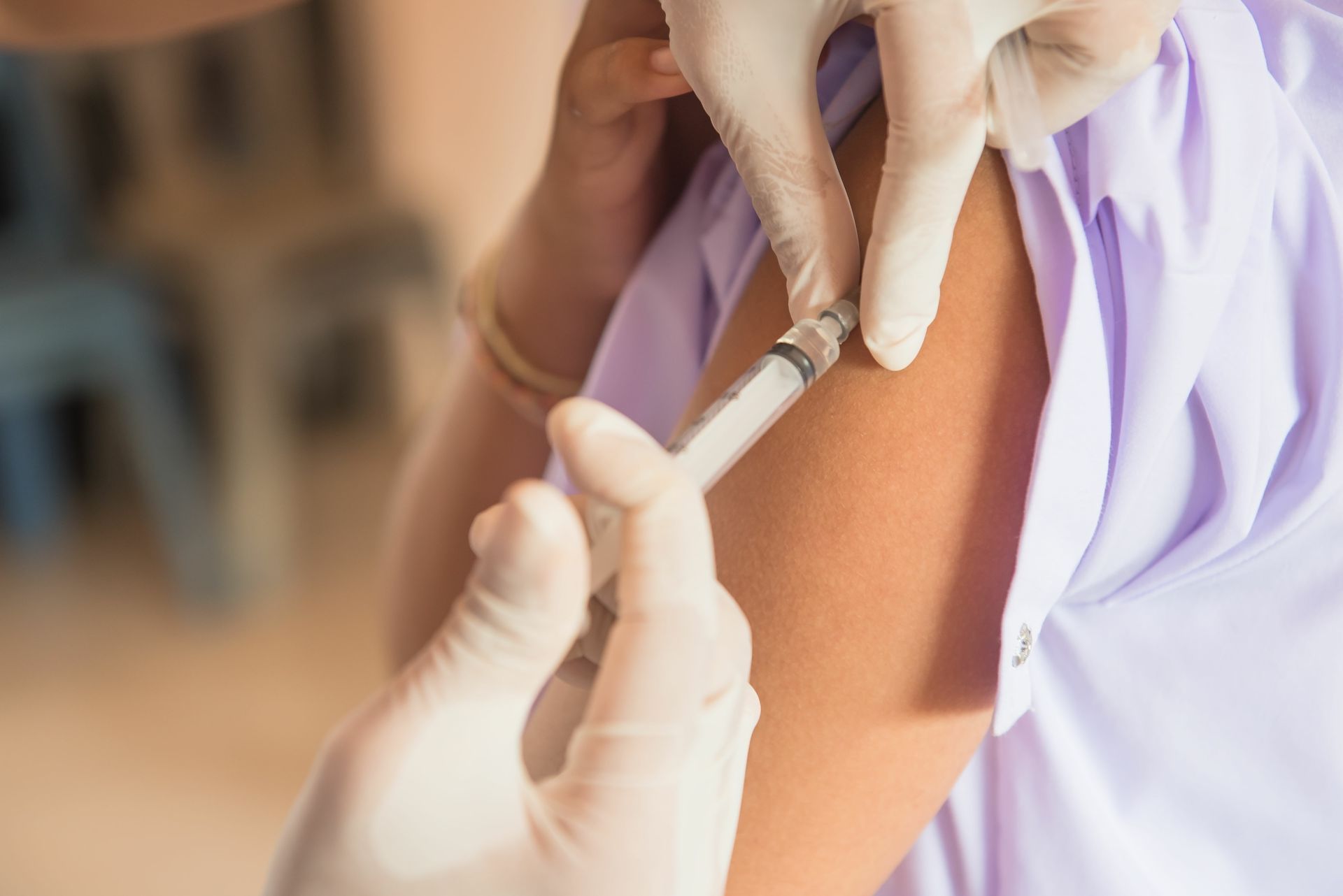 Un vaccin fait dans le bras d'une patiente en chemise violette