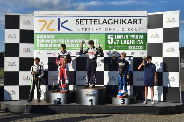 Podium mit Kartrennfahrern auf dem Settelaghikart International Circuit. Der Sieger hält den Pokal; die anderen mit Auszeichnungen.