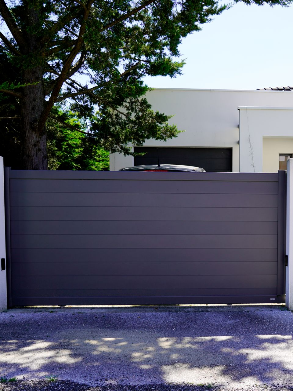 Portail devant un garage ouvert et une voiture