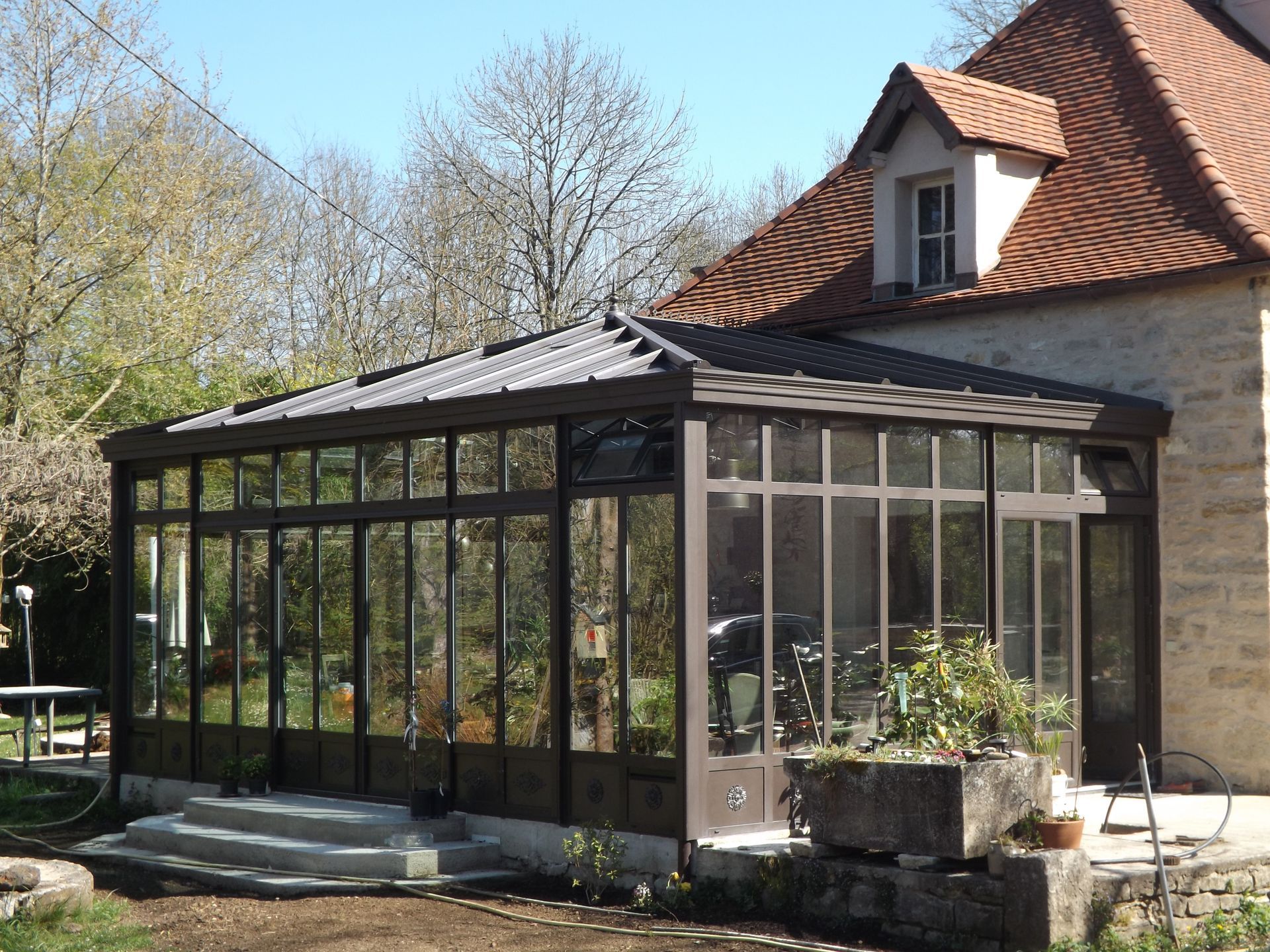 Véranda en aluminium adossée à une façade en pierre