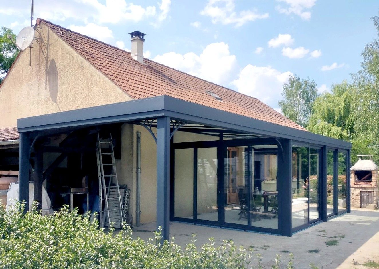 Une véranda gris foncé, avec des murs et un toit en verre