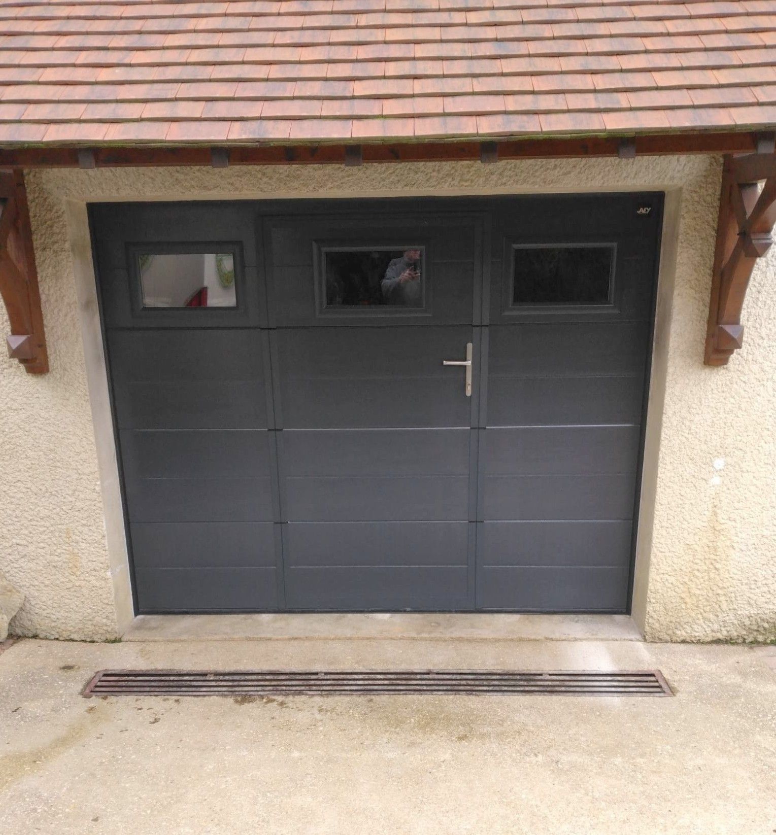 Porte de garage grise avec trois petites fenêtres