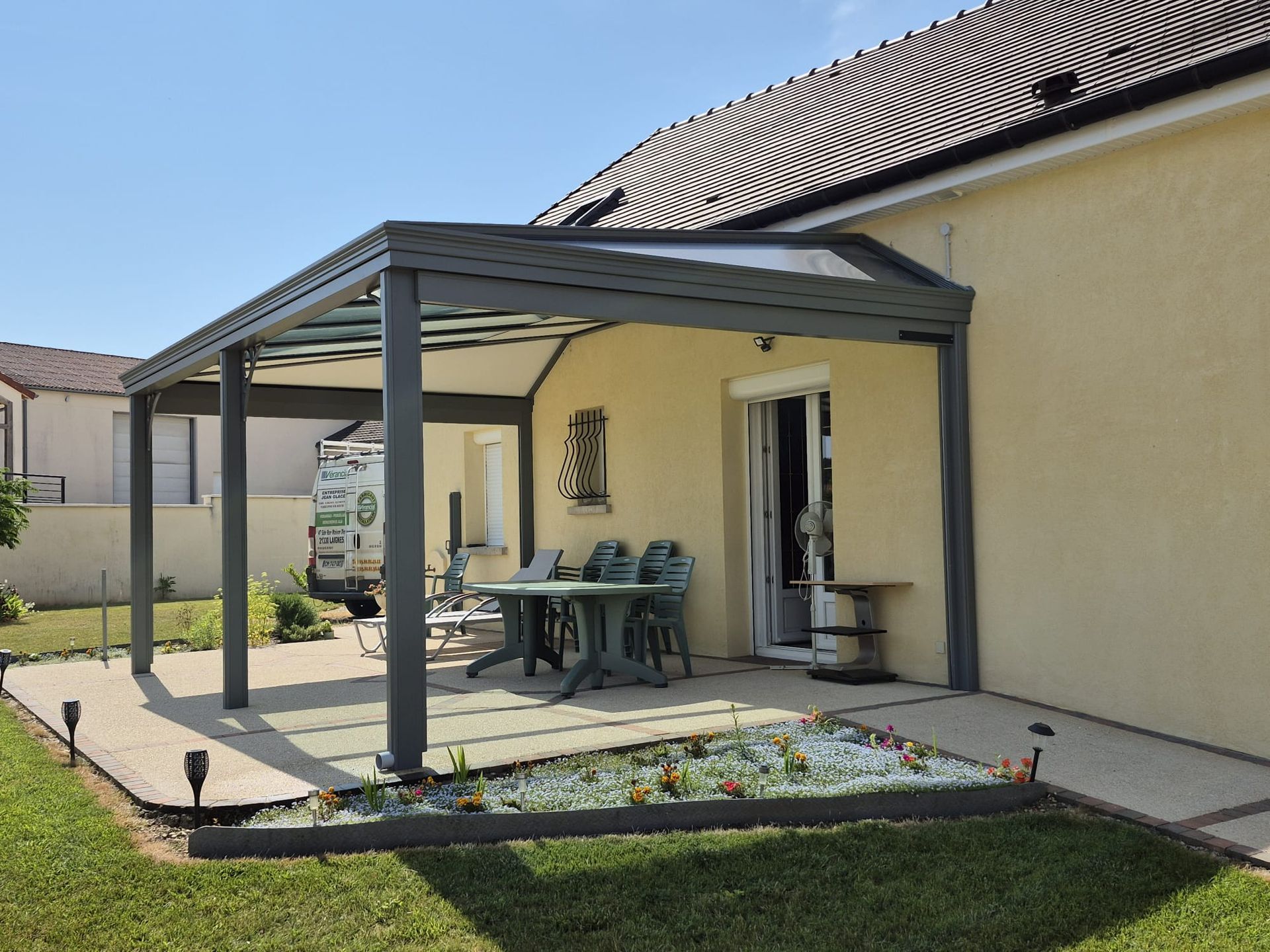 Pergola grise adossée à une maison jaune