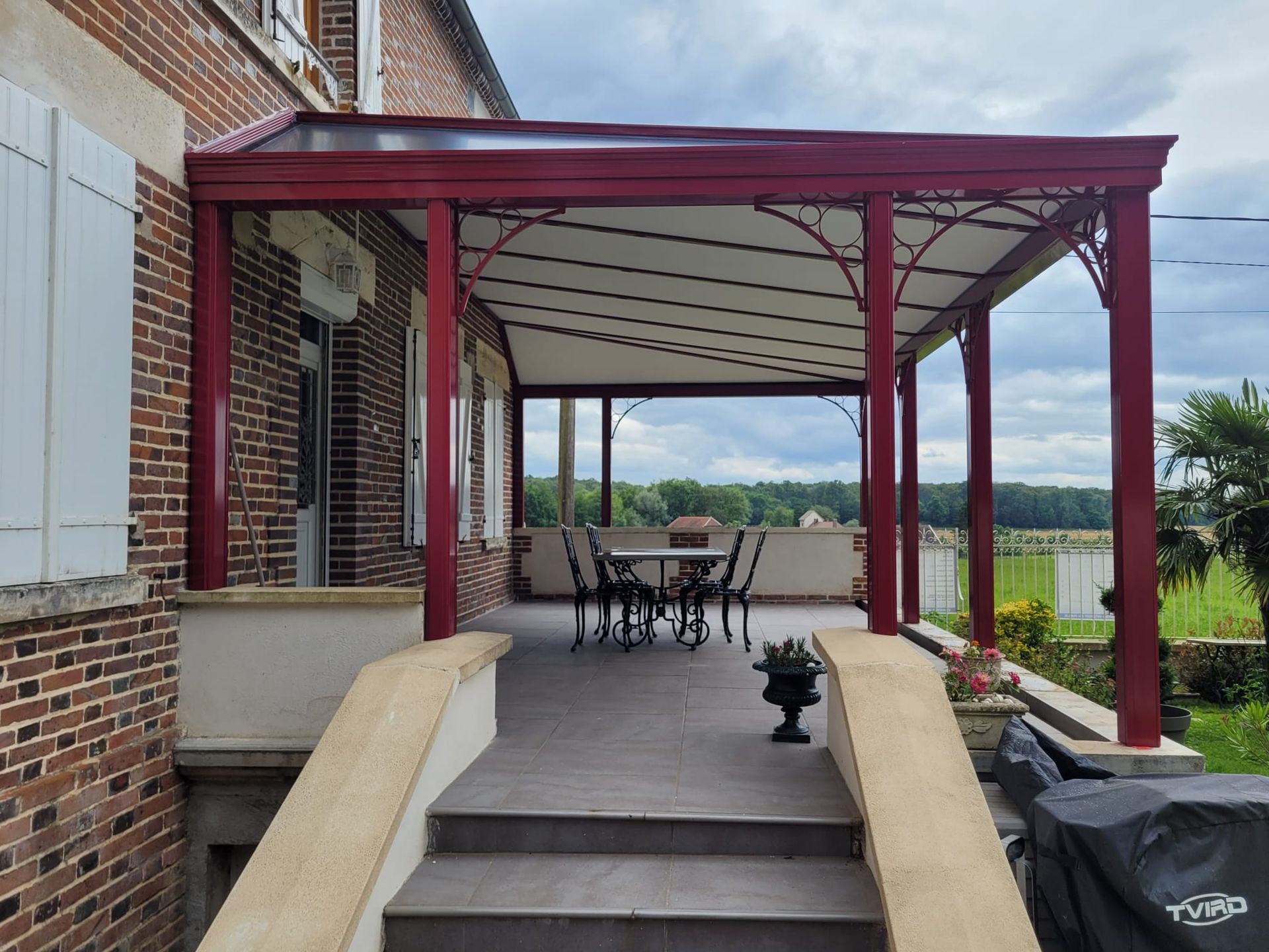 Pergola rouge surplombant une terrasse meublée
