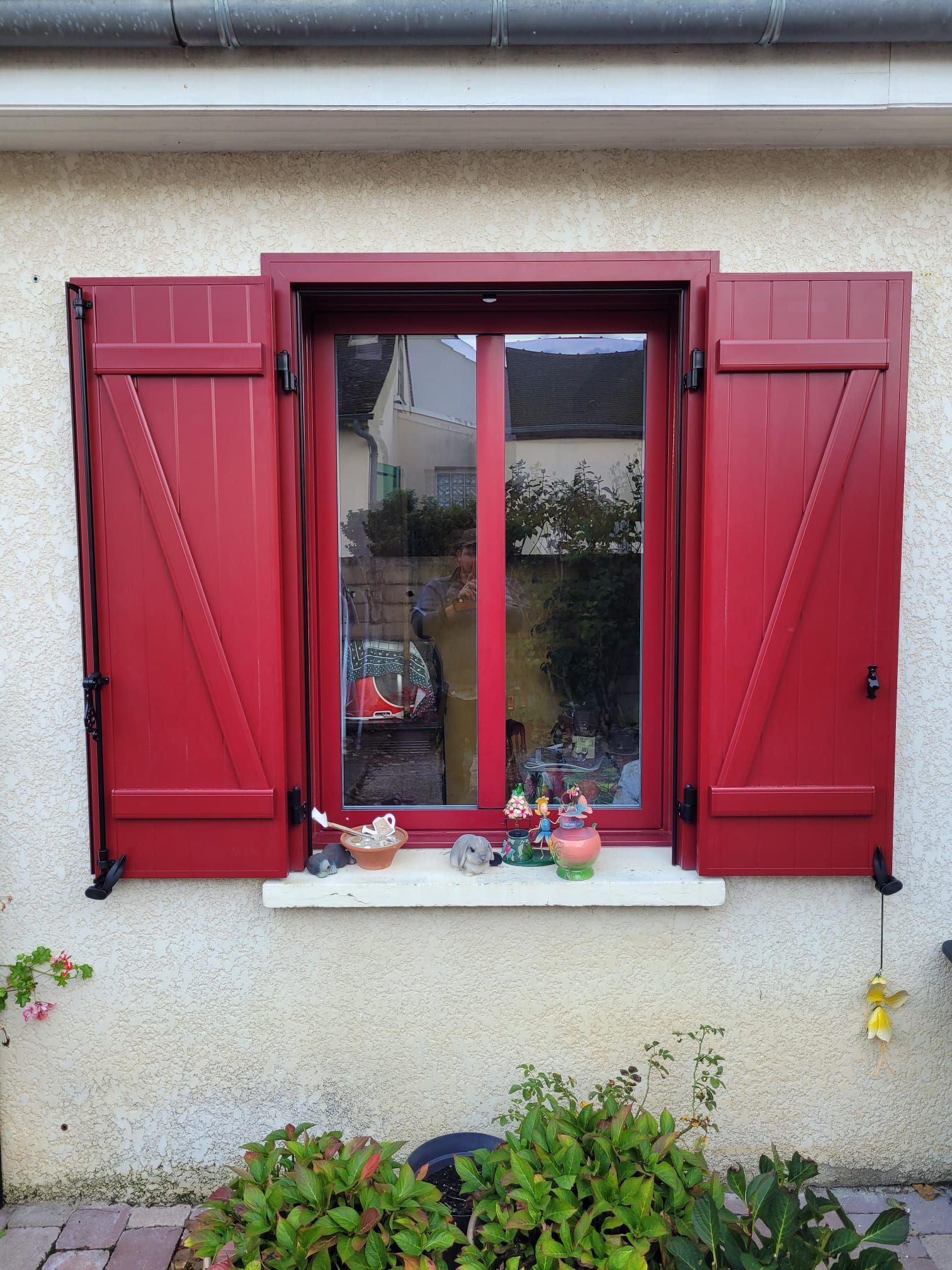 Fenêtre à volets rouges ouverts sur un mur en stuc