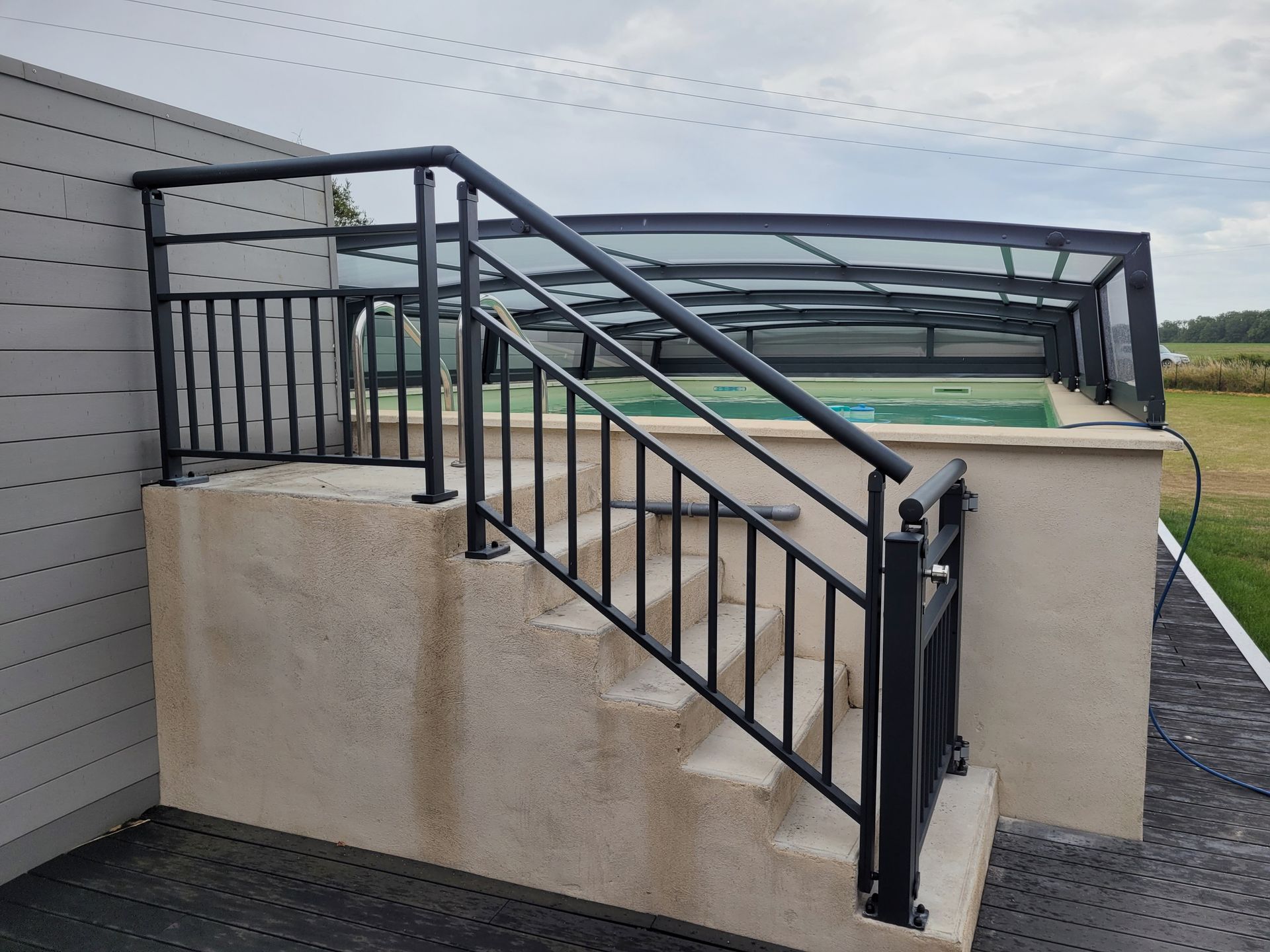Escalier extérieur avec rambarde noire menant à un bain à remous