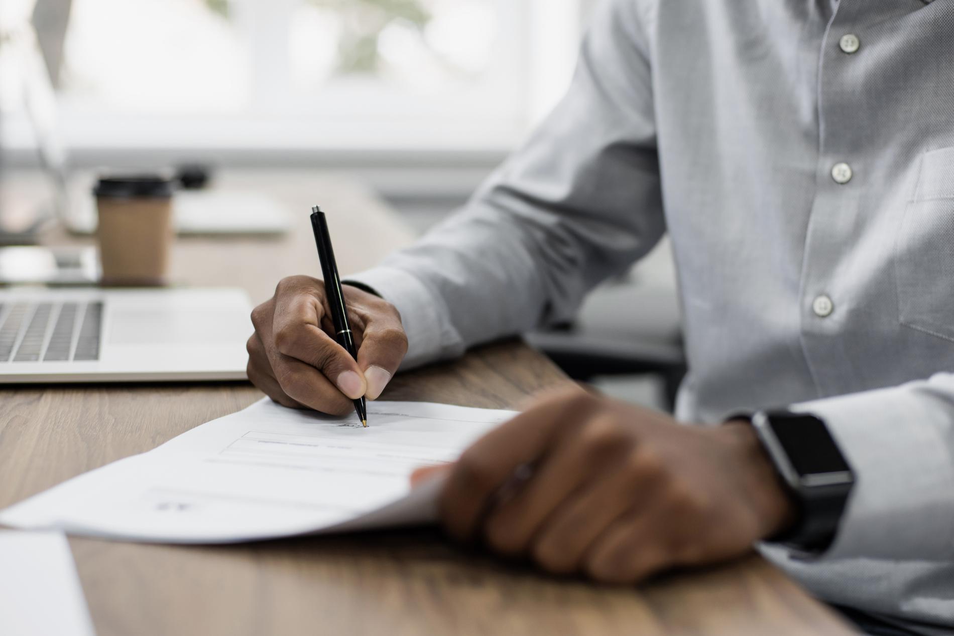 Mann sitzt am Schreibtisch und macht Notizen