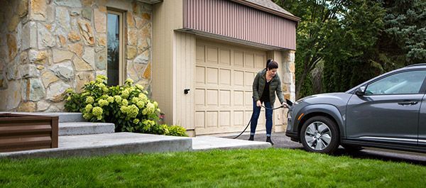 Une femme qui branche sa voiture pour la recharger