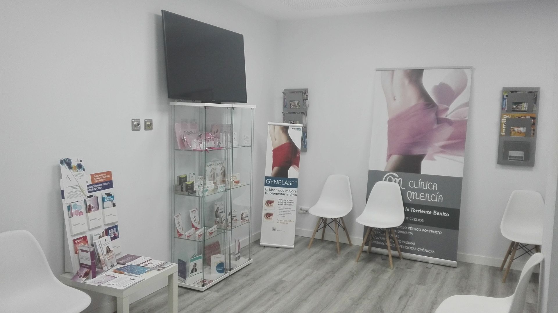 Una sala de espera con sillas, un televisor y una vitrina.