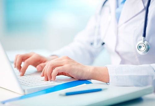 Un médico está escribiendo en una computadora portátil.