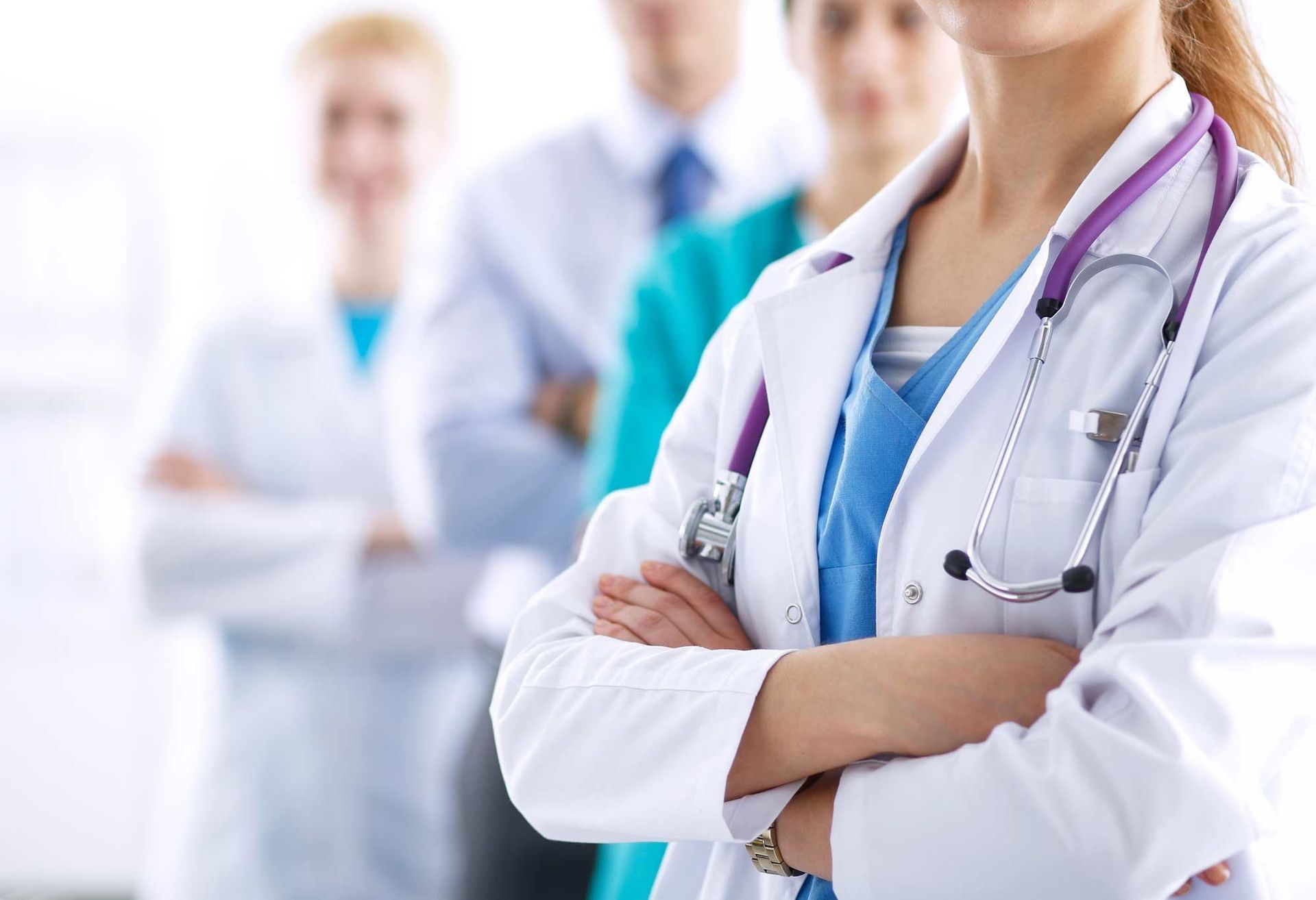 Un grupo de médicos están de pie en fila con los brazos cruzados.
