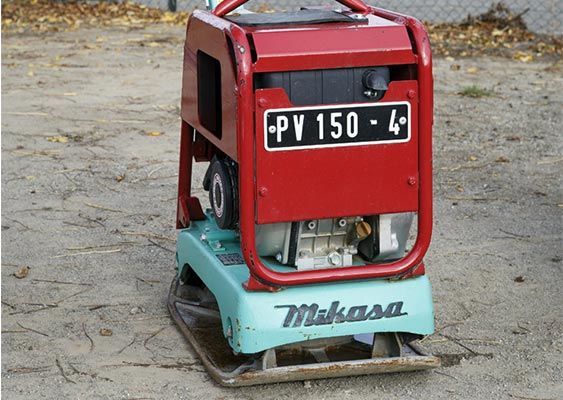 Compacteur de chantier Mikasa rouge avec base turquoise sur une surface en béton