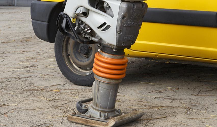 Gros plan sur la roue avant et la suspension orange d'un scooter à côté d'un véhicule jaune.