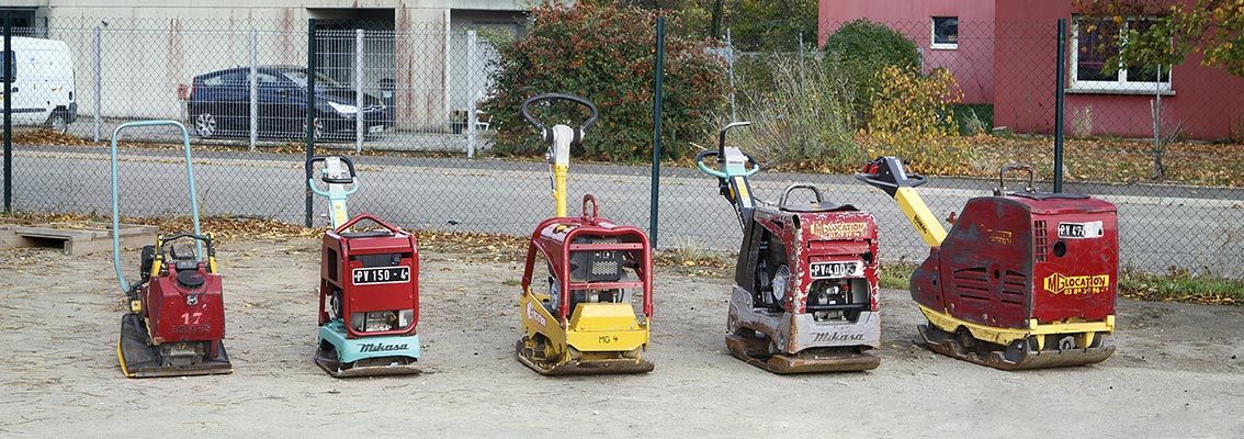Cinq petites charrettes rouges étaient alignées à l'extérieur, devant un bâtiment.