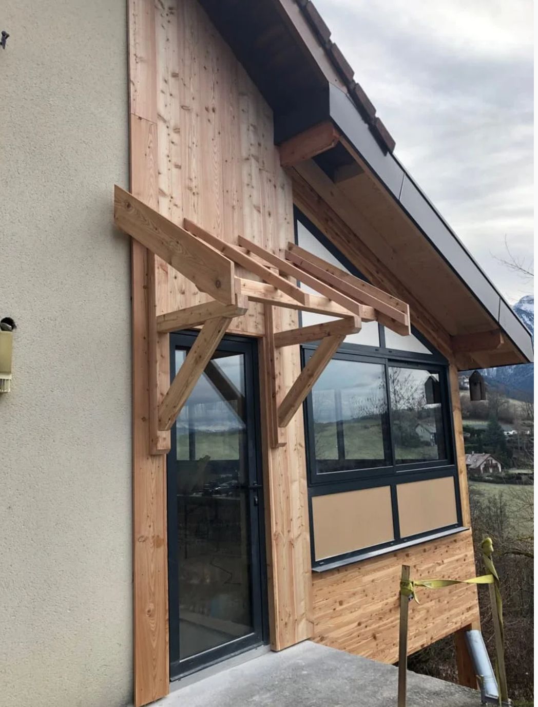 Construction en cours de la charpente d'un auvent au-dessus d'une porte.
