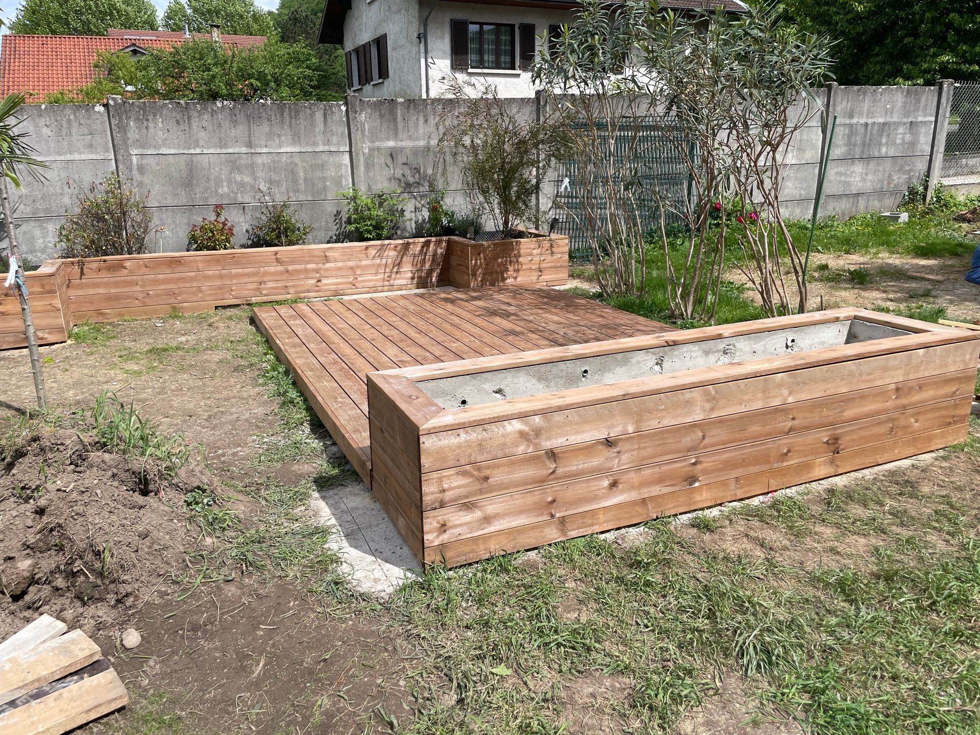 Aménagements extérieurs : terrasse entre deux bacs à fleurs en bois.