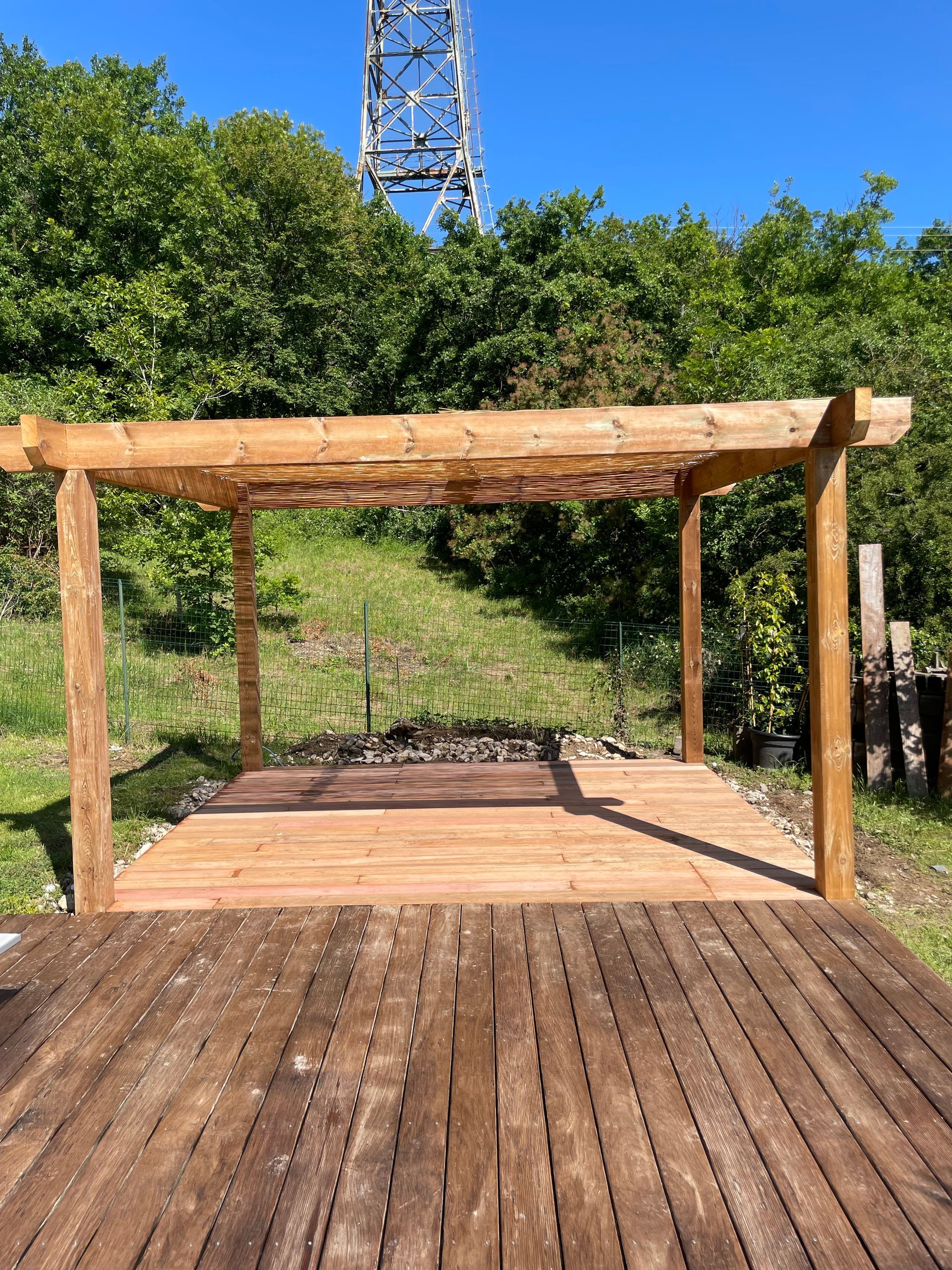 Vue de face d'une pergola en bois installée au-dessus de la moitié d'une terrasse.
