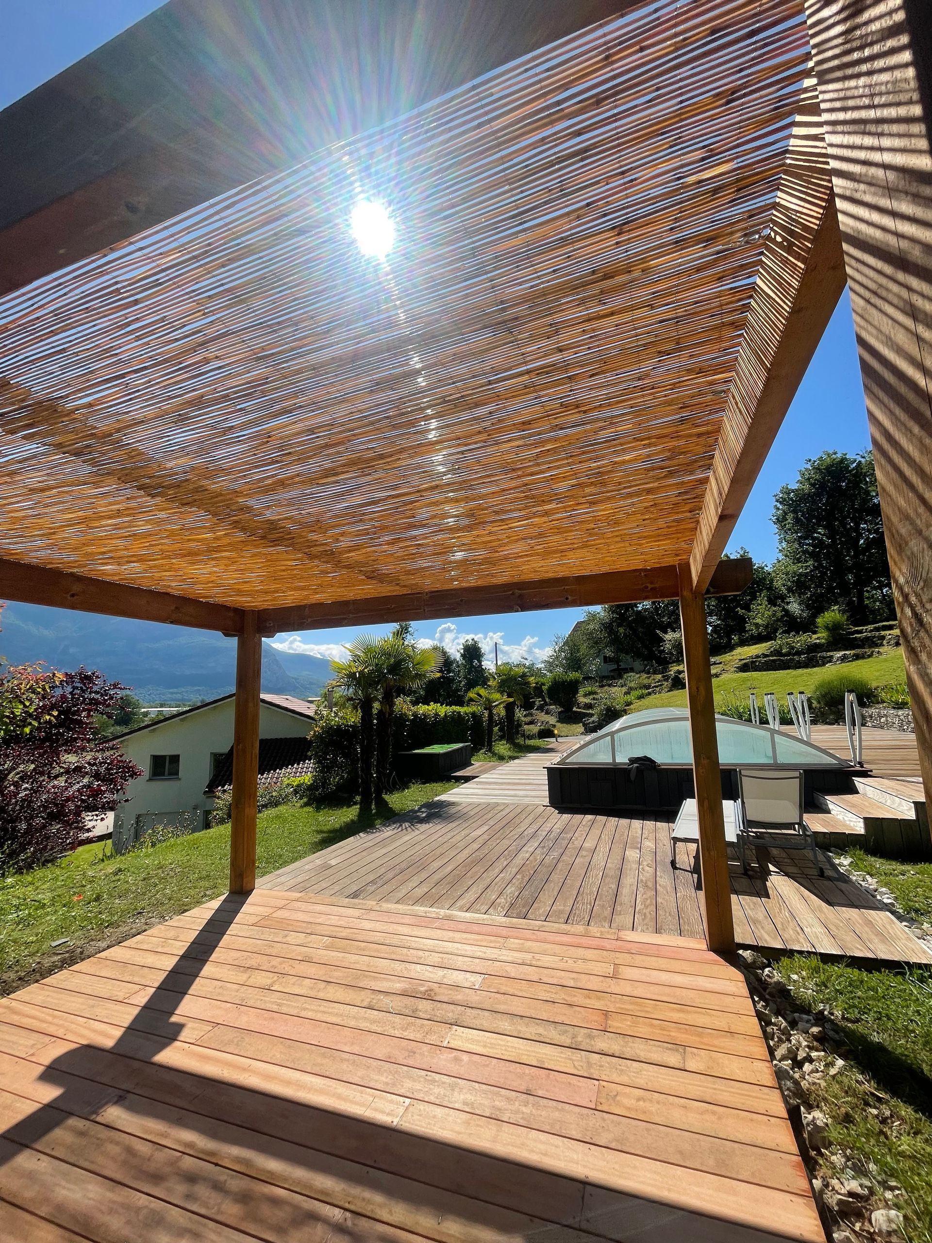 Vue de dessous d'une pergola en bois installée au-dessus d'une terrasse en bois.