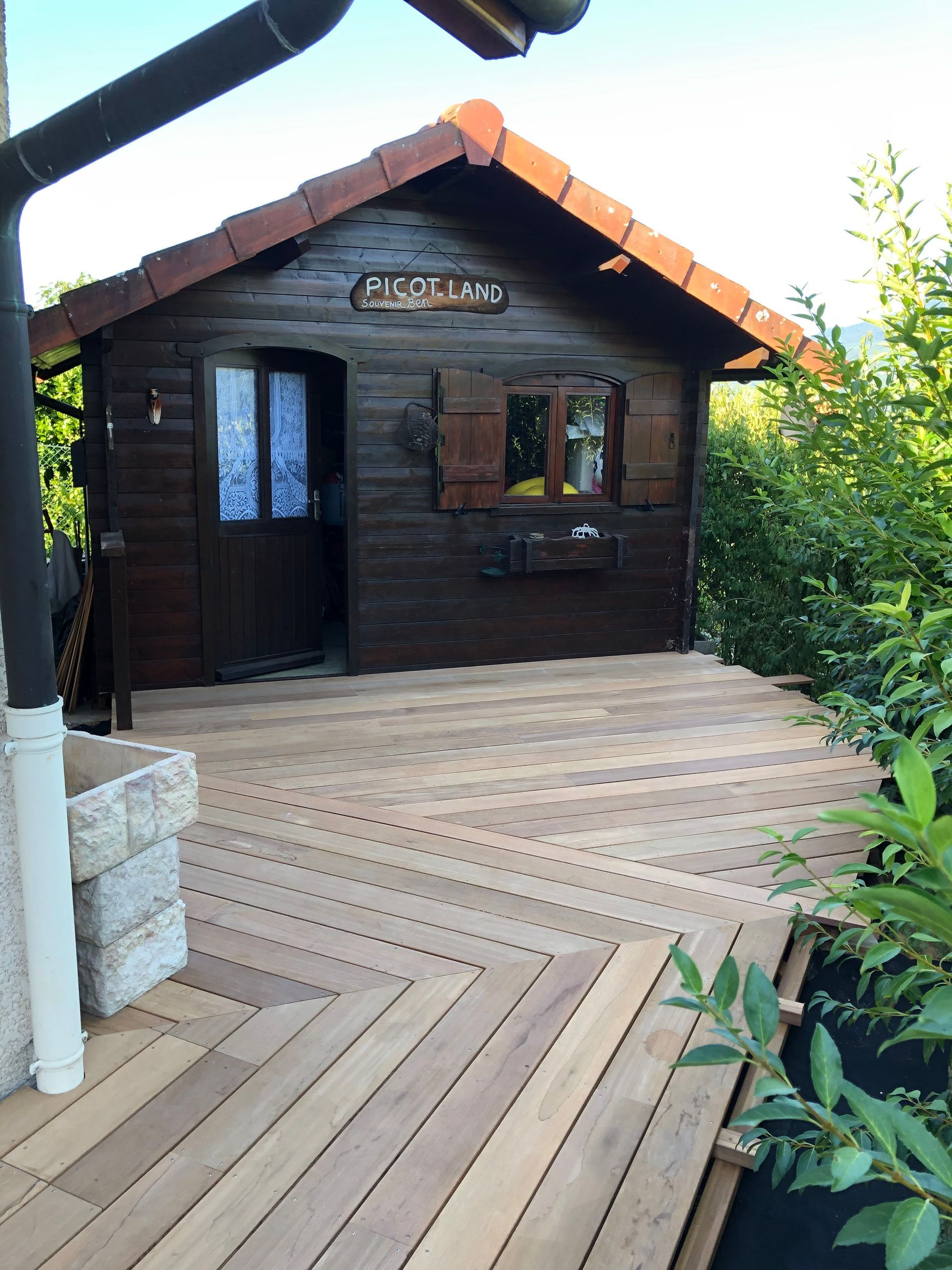 Chemin et terrasse en bois construits pour mener à une petite maisonnée en bois avec la mention Picotland.