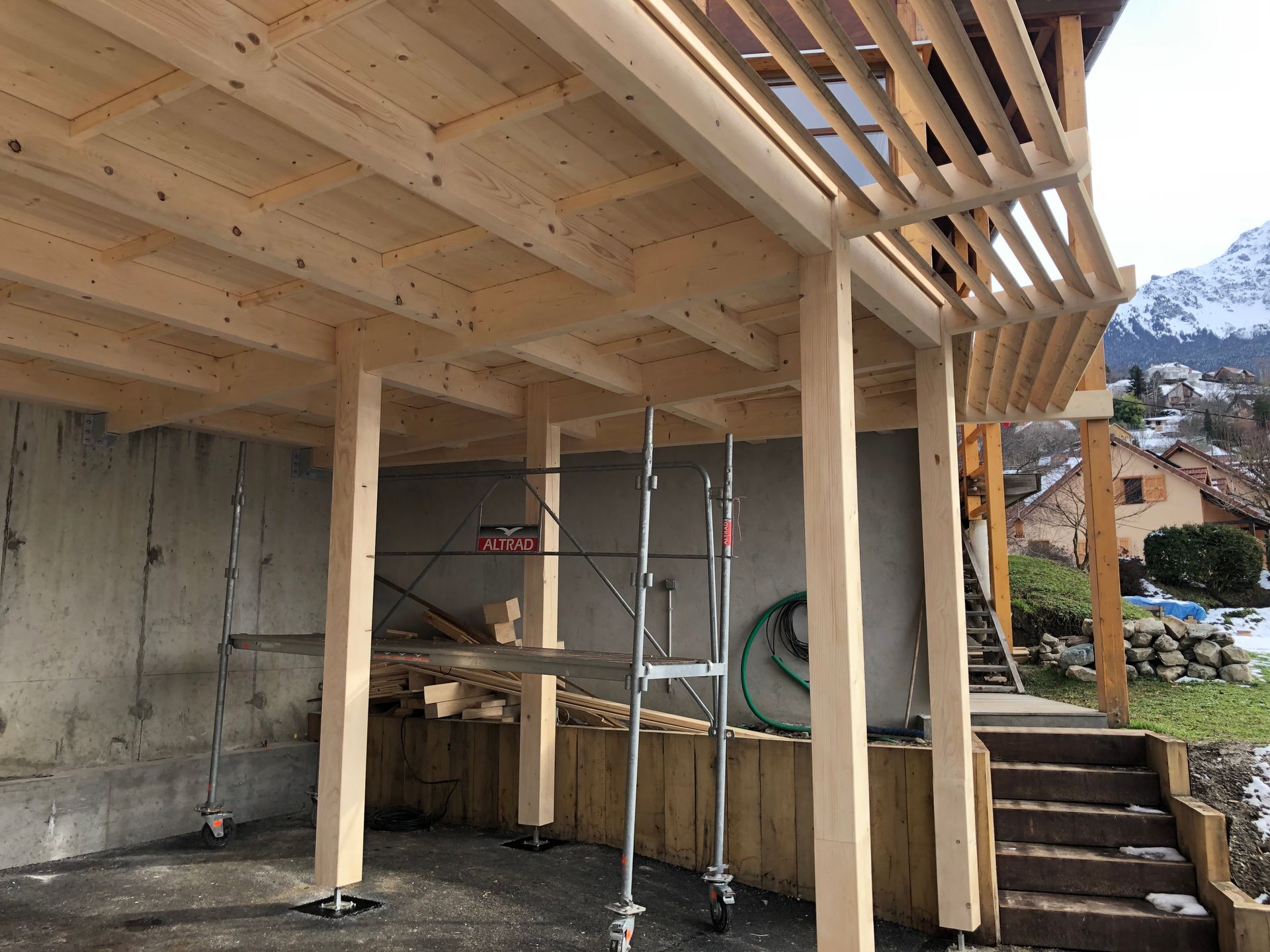 Installation en cours des poutres et de la charpente d'un abri de voiture.