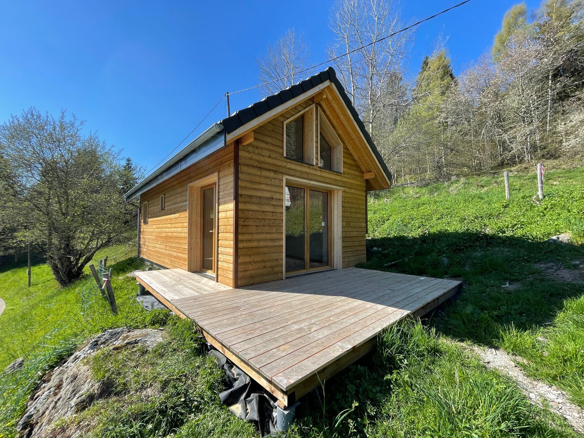 Construction d'une terrasse en bois terminée autour d'une petite maison.