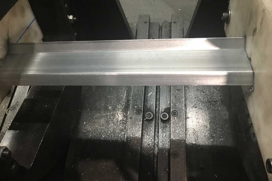 Viga de metal sujetada en una sierra, lista para cortar.