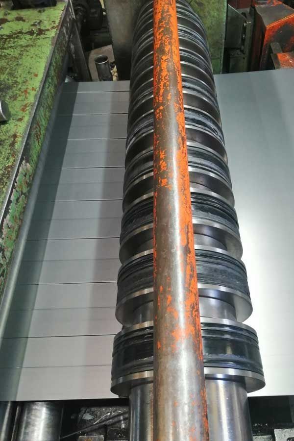 Chapa metálica cortada mediante una máquina cortadora con múltiples cuchillas circulares; entorno industrial.