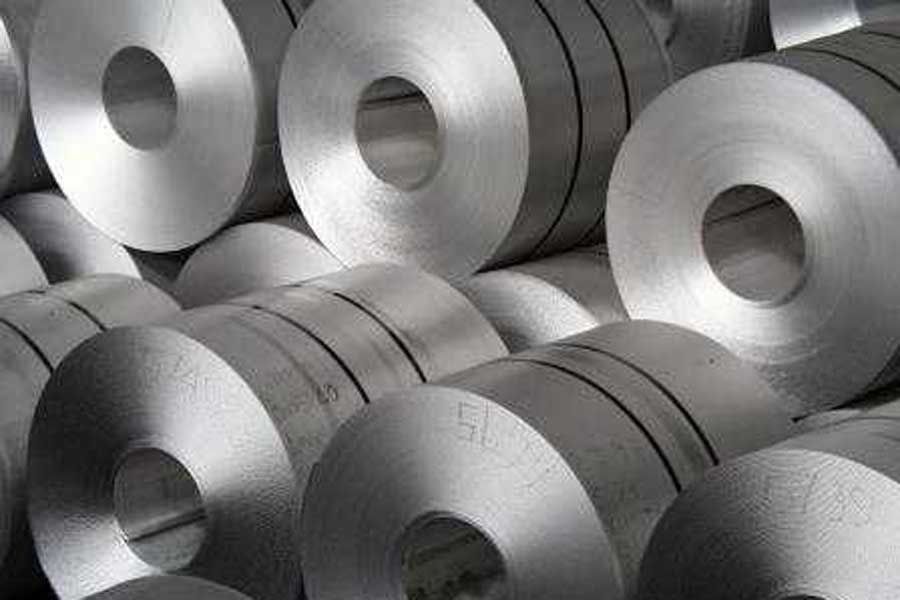 Bobinas de acero apiladas. Cilindros metálicos brillantes con orificios centrales. Entorno industrial.