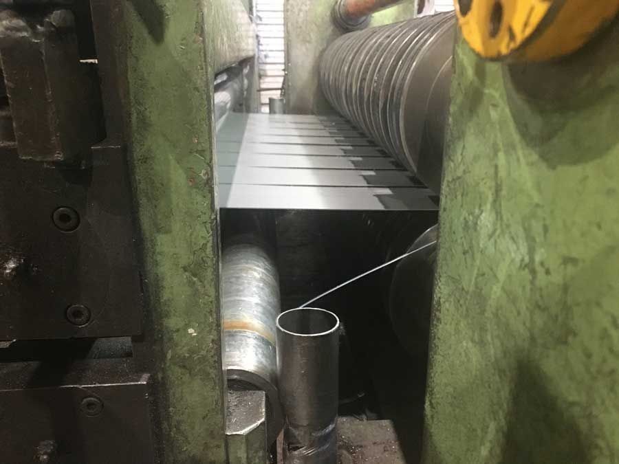 Máquina cortadora de bobinas de acero que corta láminas de metal en una fábrica.