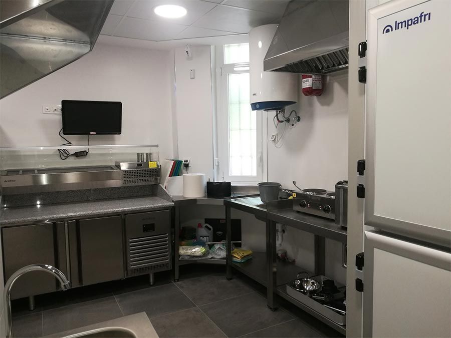 Una cocina con electrodomésticos de acero inoxidable, un fregadero y un refrigerador.