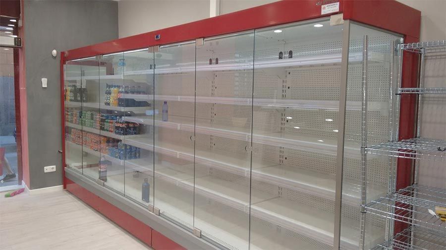Una fila de estantes vacíos en una tienda con puertas de vidrio.