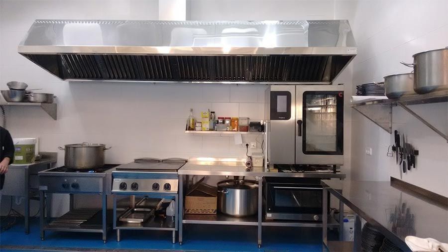 Una cocina con muchos electrodomésticos de acero inoxidable y ollas y sartenes.