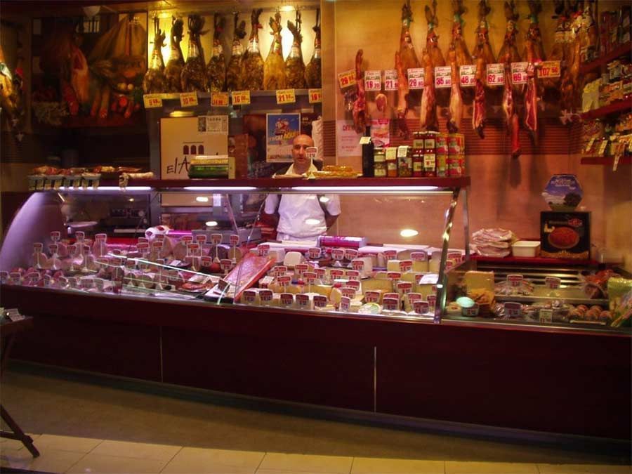 Un hombre está de pie detrás de un mostrador en una tienda de comestibles.