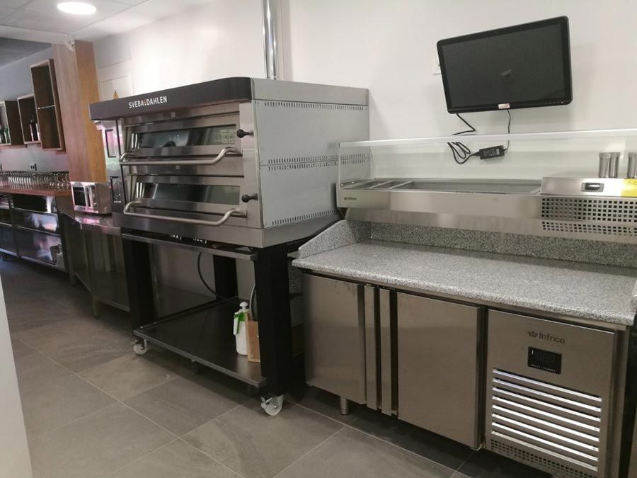 Una cocina con electrodomésticos de acero inoxidable y un televisor en la pared.