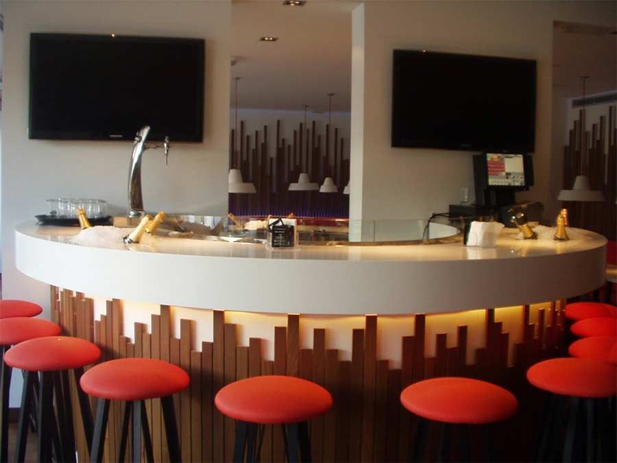 Un bar con taburetes rojos y un televisor en la pared.