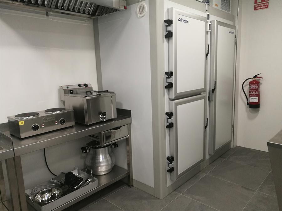 Una cocina con electrodomésticos de acero inoxidable y un extintor de incendios en la pared.