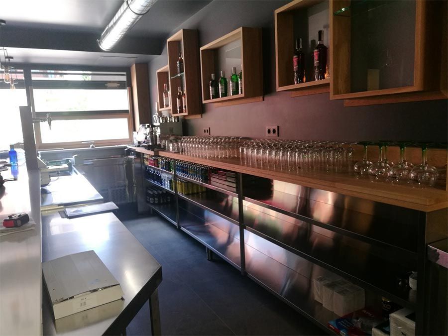 Una cocina con muchas botellas y vasos en los estantes.