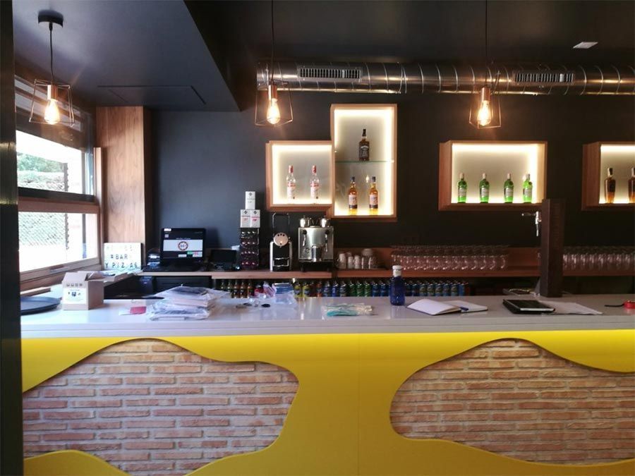 Un bar con un mostrador amarillo y una pared de ladrillos.