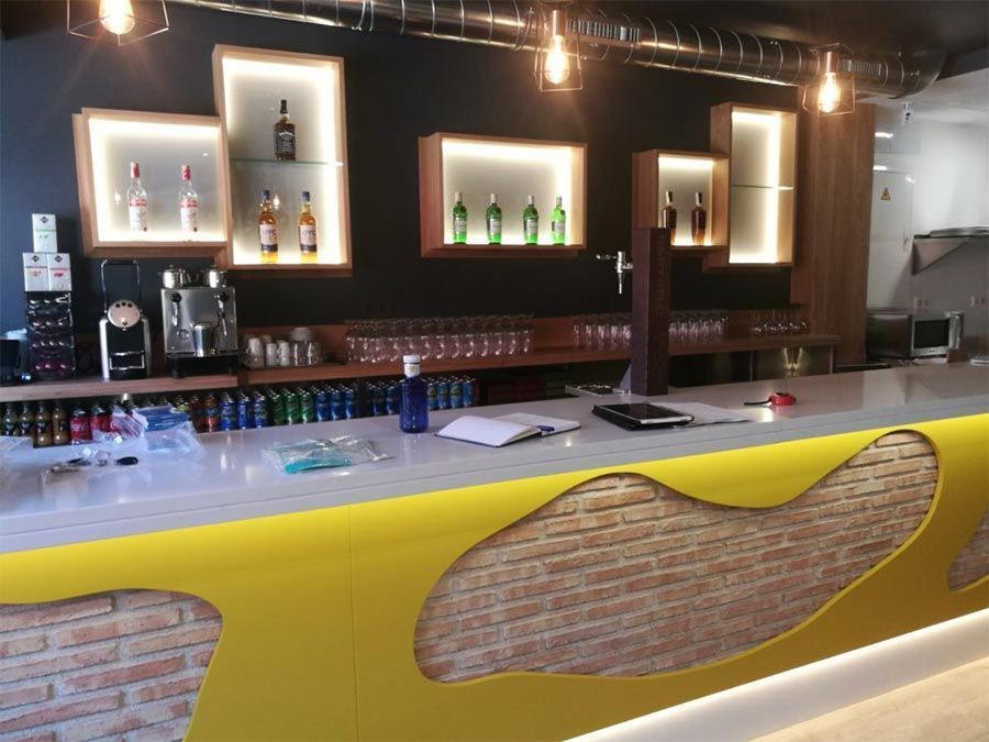 Un bar con un mostrador amarillo y una pared de ladrillos.
