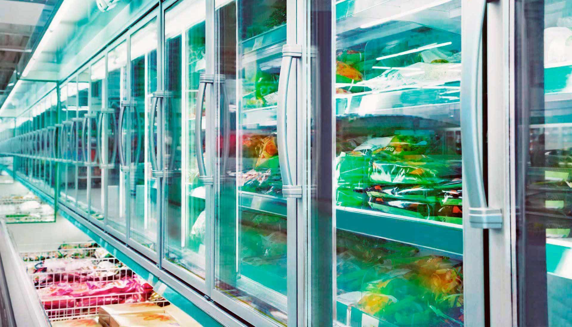 Una fila de refrigeradores en una tienda de comestibles llenos de comida.